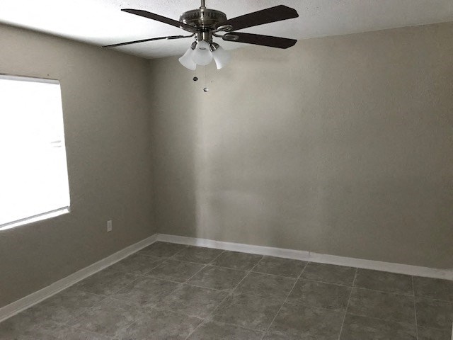 an empty room with a ceiling fan and a window