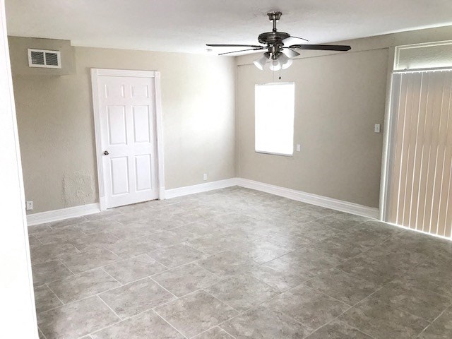 an empty living room with a ceiling fan