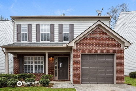 a home with a garage door and a white house