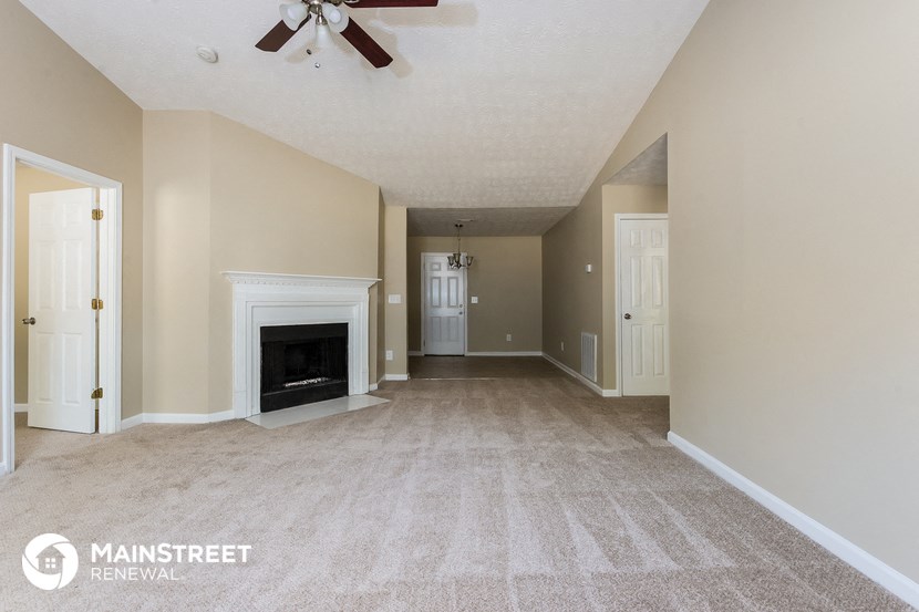 an empty living room with a fireplace and a ceiling fan