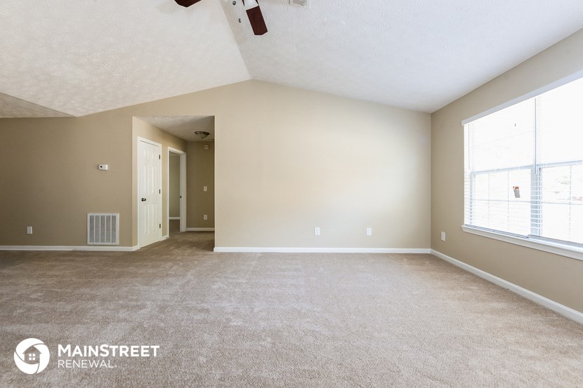 the spacious living room with carpeted flooring and large windows