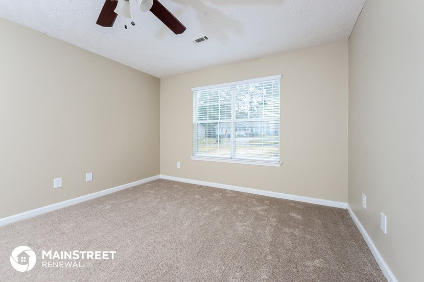 the spacious bedroom with carpeted flooring and a large window