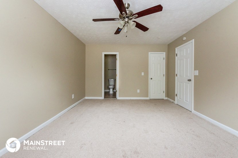 an empty living room with a ceiling fan and a closet