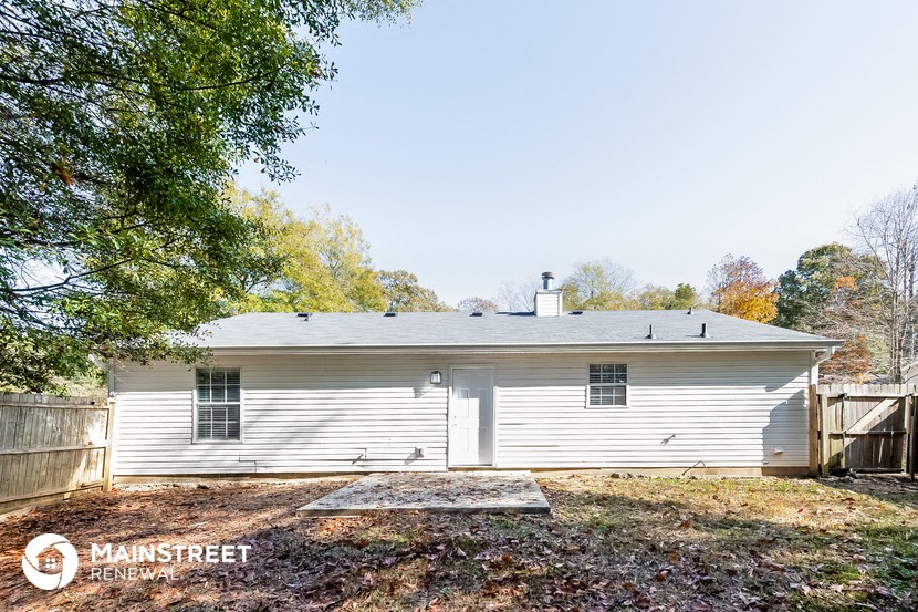 the back of a white house with a yard and trees