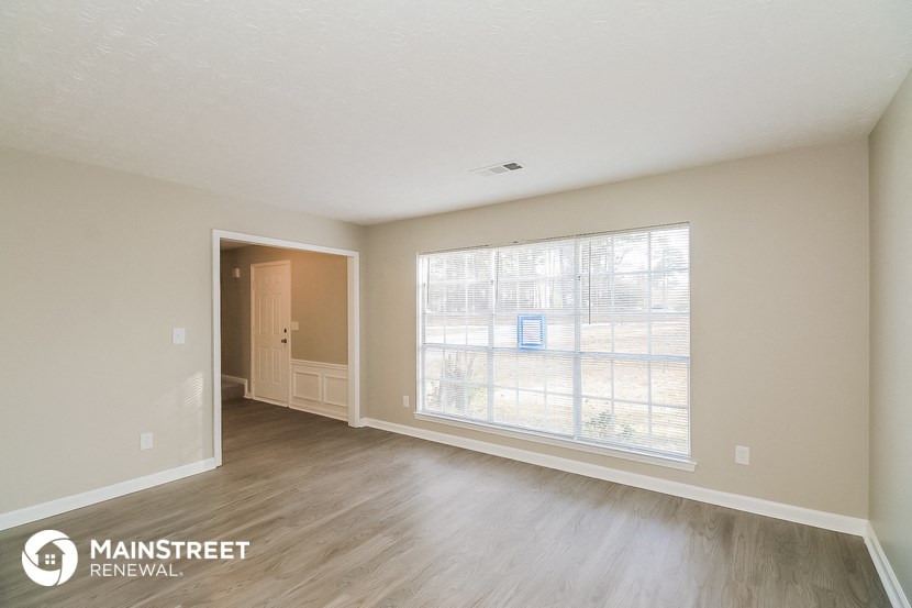 the living room of an apartment with wood flooring and a large window