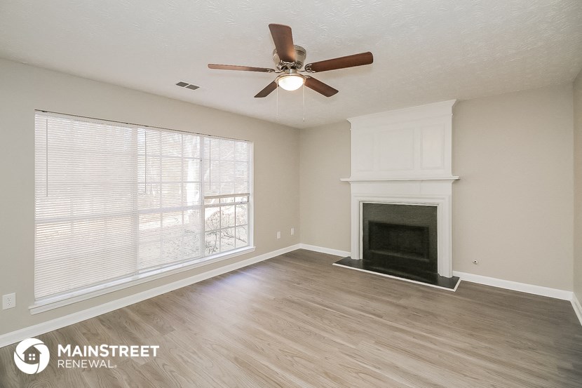 a living room with a fireplace and a ceiling fan