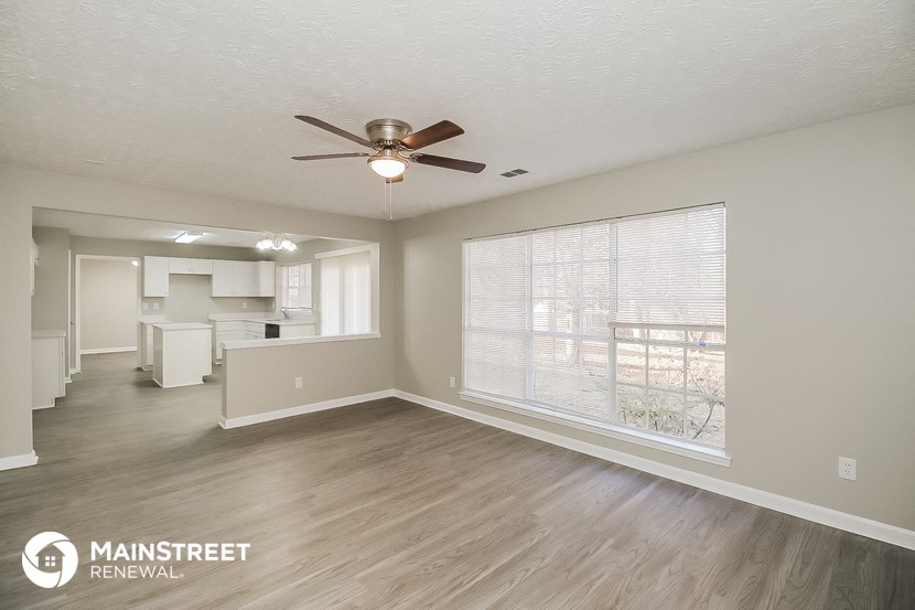 an empty living room with a ceiling fan and a large window