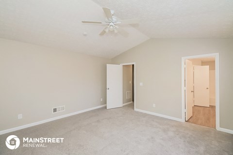 the spacious living room with carpet and a ceiling fan