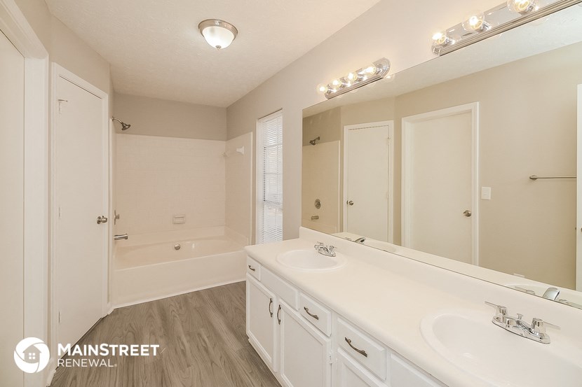 a bathroom with two sinks and a tub and a large mirror