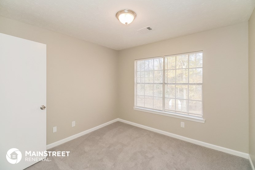 a bedroom with a large window and carpeted flooring