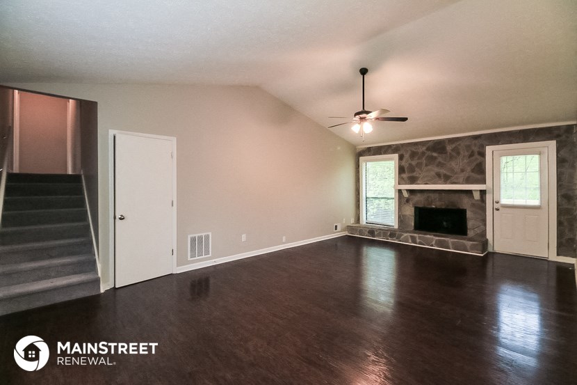 an empty living room with a fireplace and a ceiling fan