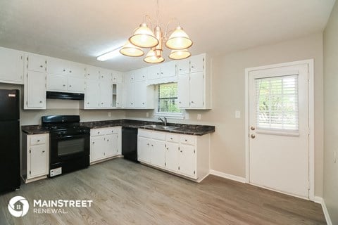 the kitchen of an apartment with white cabinets and black appliances