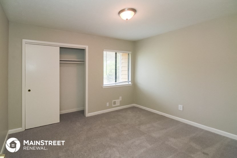 a bedroom with a closet and a window and a carpeted floor