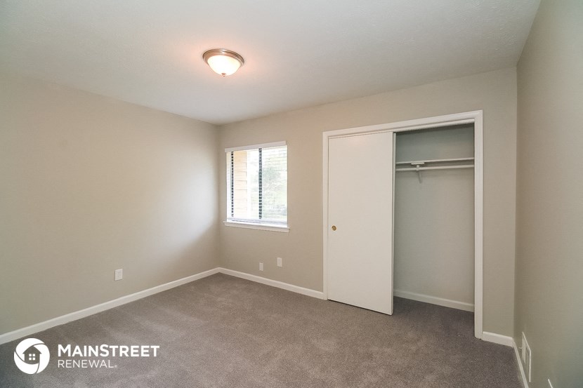 the bedroom of an apartment with a closet and a window