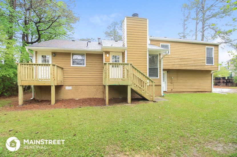 the front of a yellow house with a porch and a deck