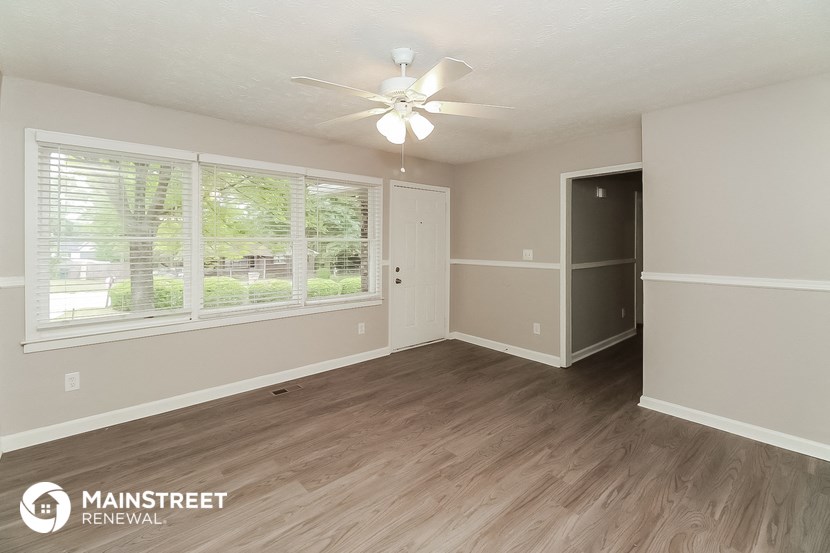 the living room of an apartment with wood flooring and a ceiling fan