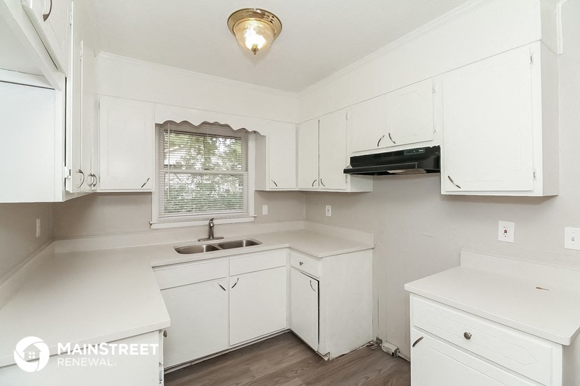 a white kitchen with white cabinets and a sink
