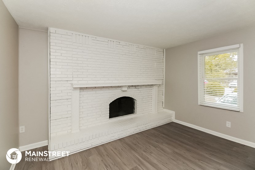 the living room of a house with a white brick fireplace