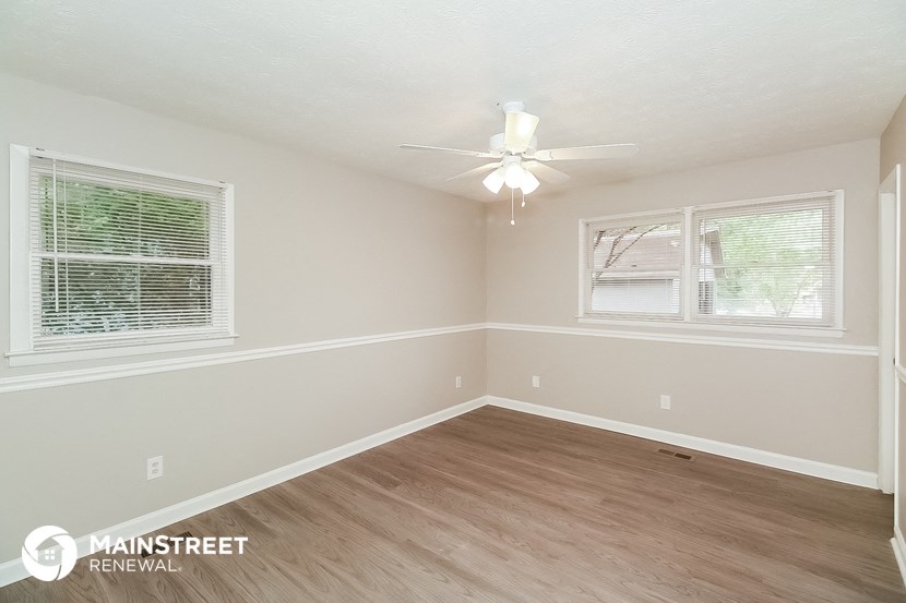 the living room of a house with wood floors and a ceiling fan