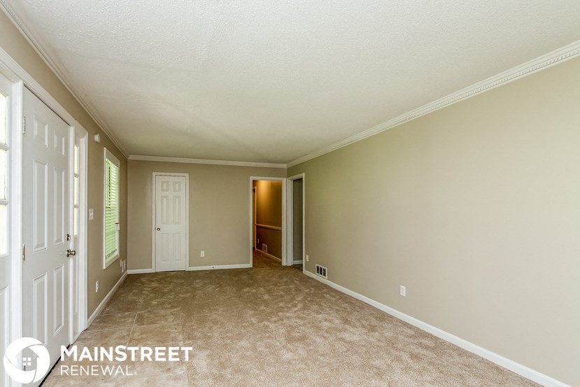 an empty living room with a door to a hallway