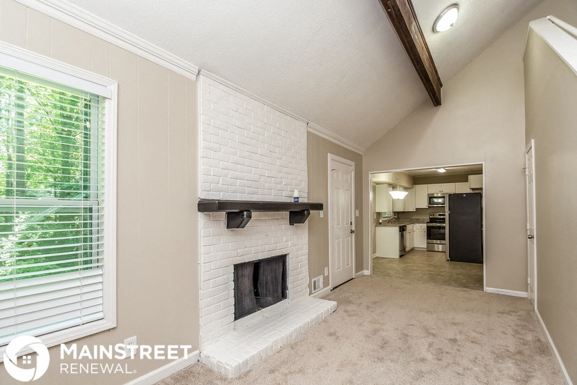 a living room with a white brick fireplace and a large window