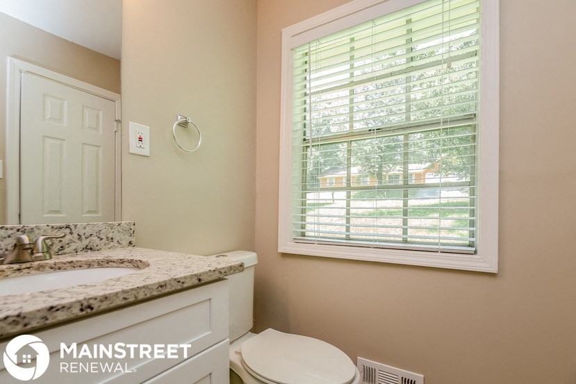 a bathroom with a toilet and sink and a window