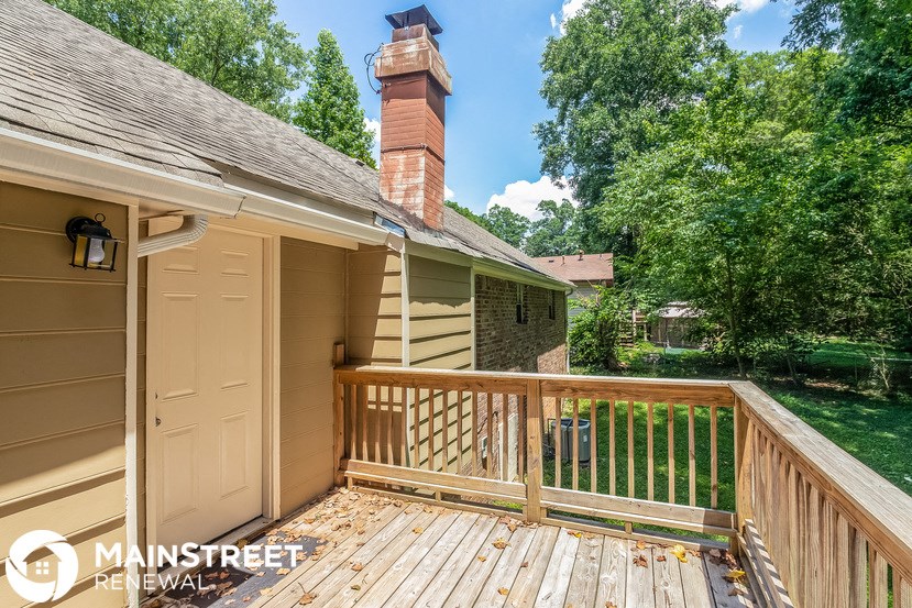 a deck overlooking a backyard with a pond and a house