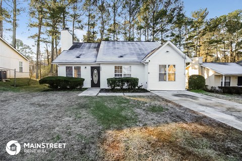 a small white house with a yard and trees