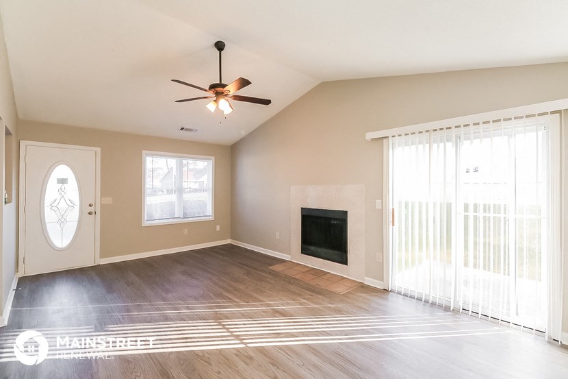 the living room of an empty house with a fireplace and a ceiling fan
