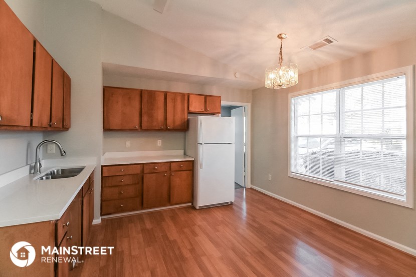 an empty kitchen with wooden cabinets and a white refrigerator