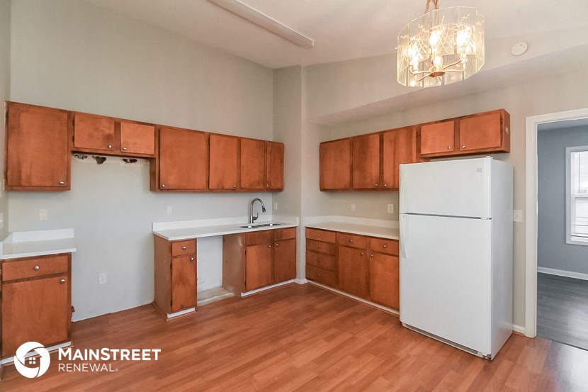 an empty kitchen with wooden cabinets and a white refrigerator
