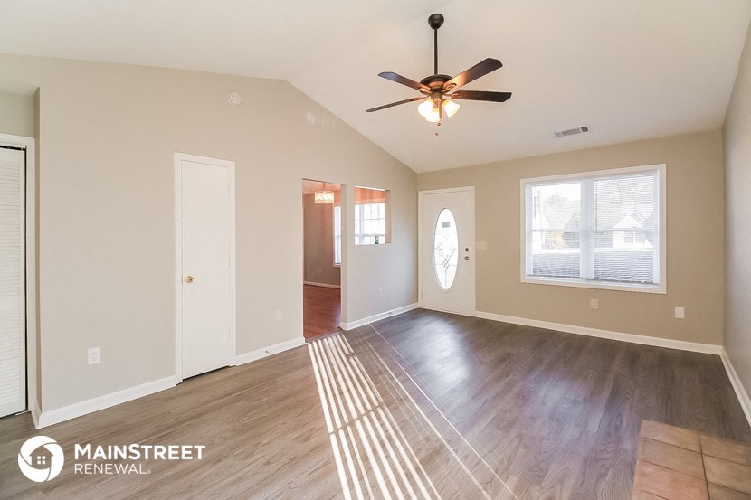 the living room and dining room with wood flooring and a ceiling fan