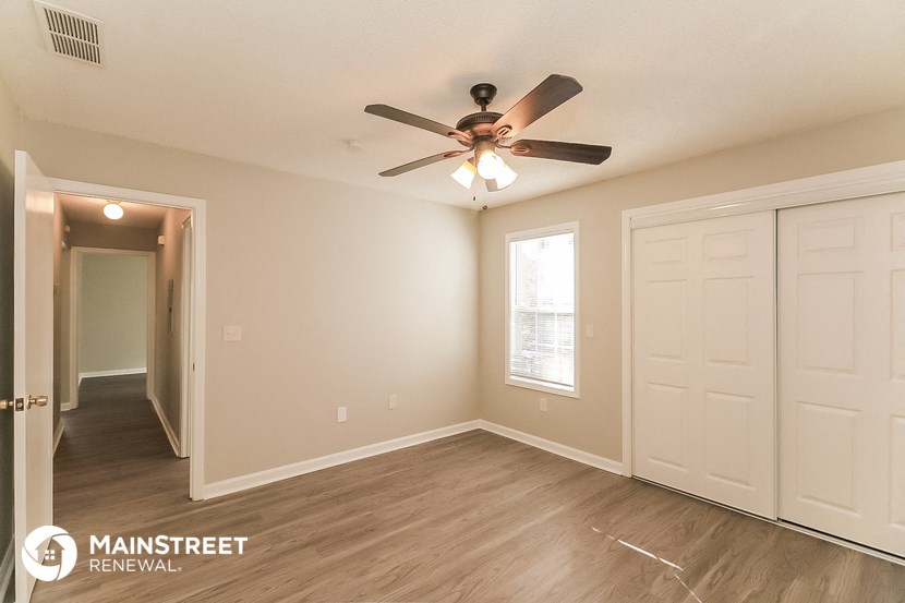 a living room with a ceiling fan and a door to a hallway