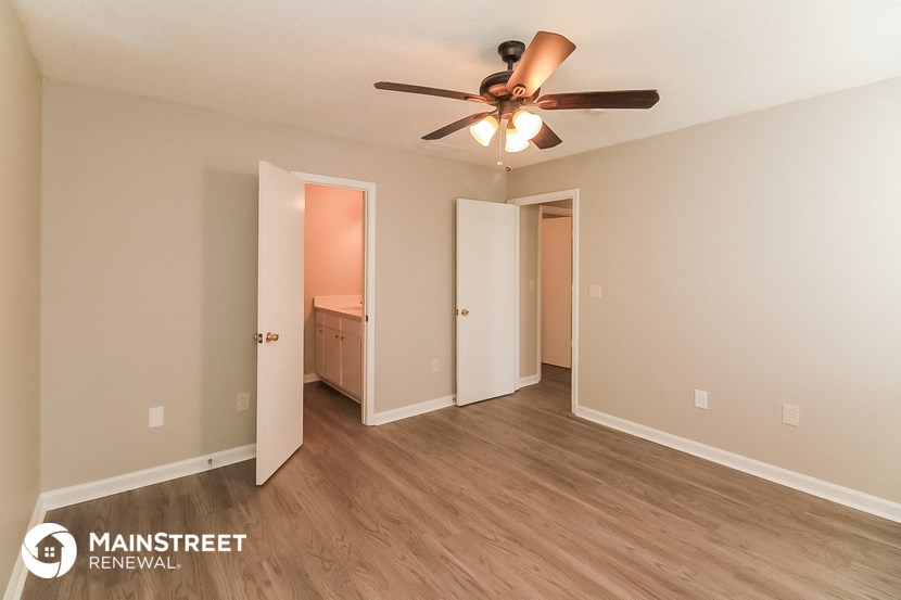 the living room of an apartment with wood flooring and a ceiling fan