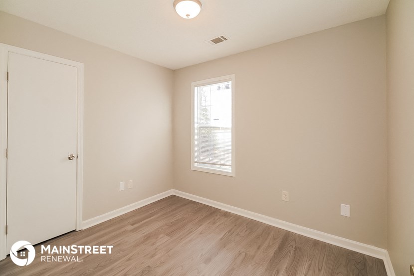 a bedroom with wood flooring and white walls and a window