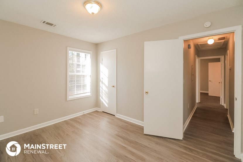 the living room and hallway of an apartment with white walls and wood flooring