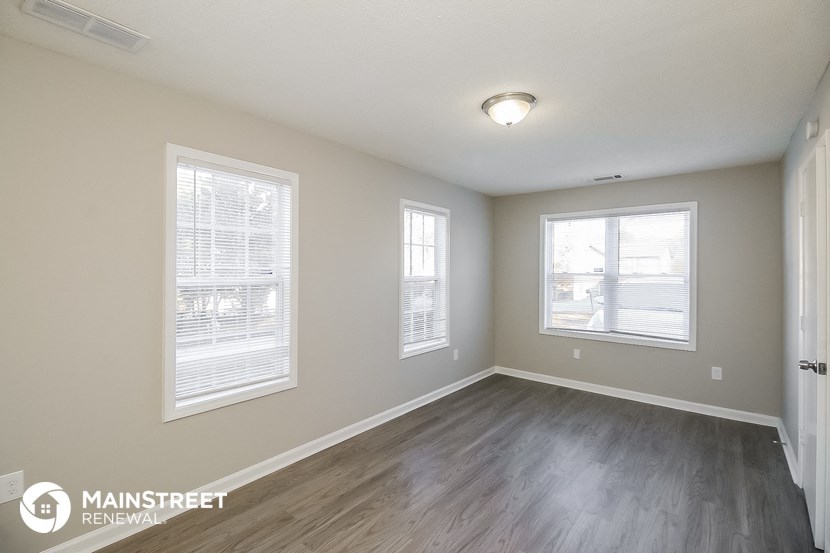 the spacious living room with wood flooring and two windows