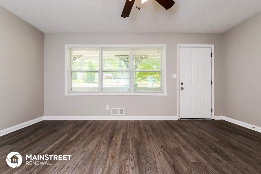 the living room of a renovated house with wood floors and a white door