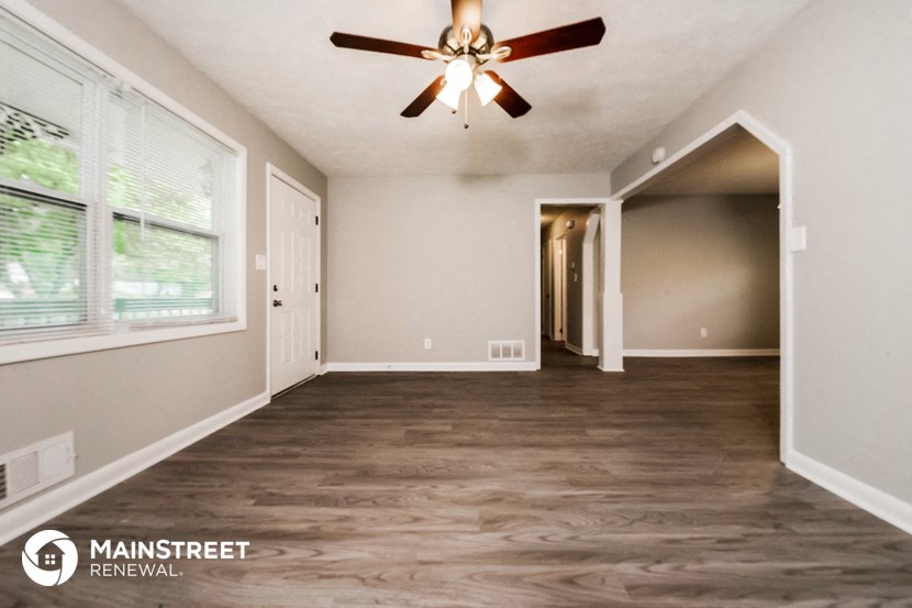 an empty living room with wood flooring and a ceiling fan