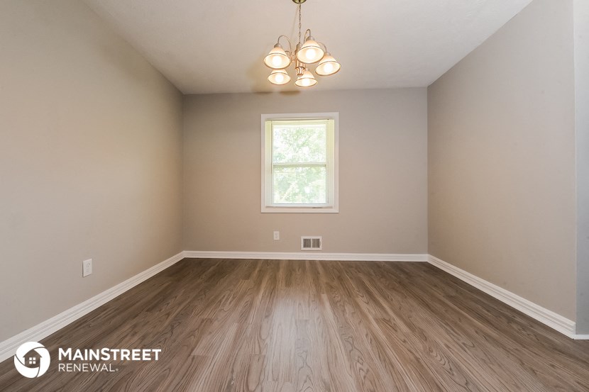 the spacious living room with wood flooring and a window