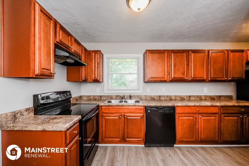 a kitchen with wooden cabinets and a black dishwasher and a sink
