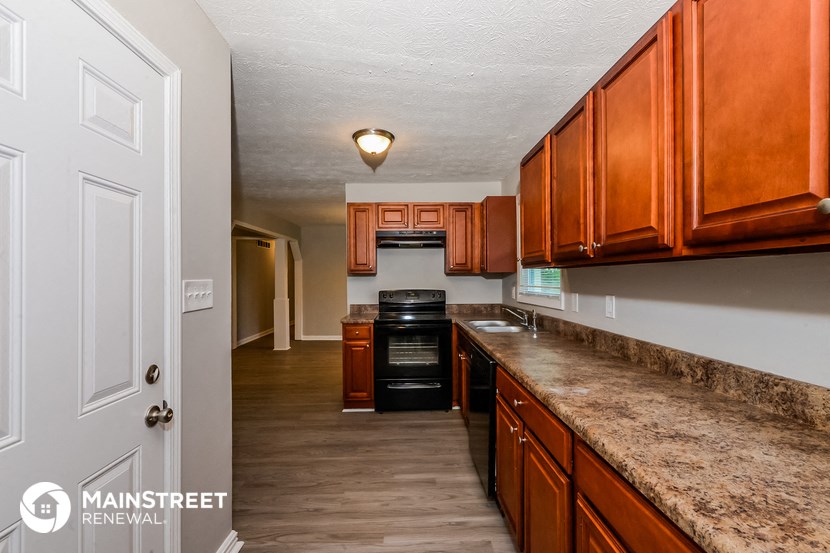 a kitchen with wooden cabinets and a long counter top and a black stove