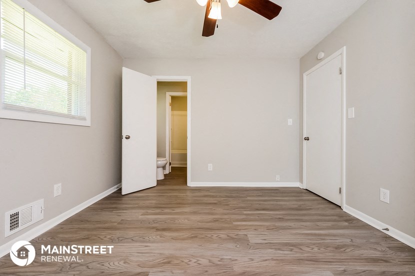 the spacious living room with a ceiling fan and wood flooring