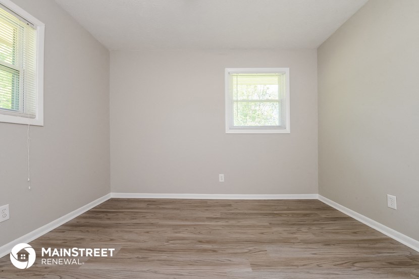 the interior of an empty room with wooden floors and two windows