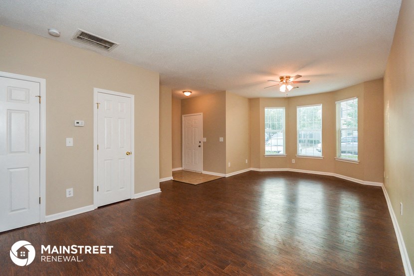 an empty living room with wood floors and a ceiling fan