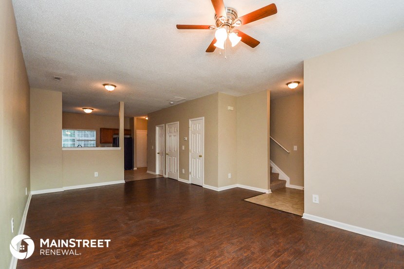 an empty living room with a ceiling fan