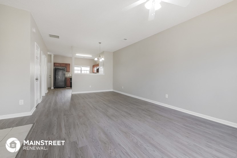 an empty living room with wood flooring and white walls