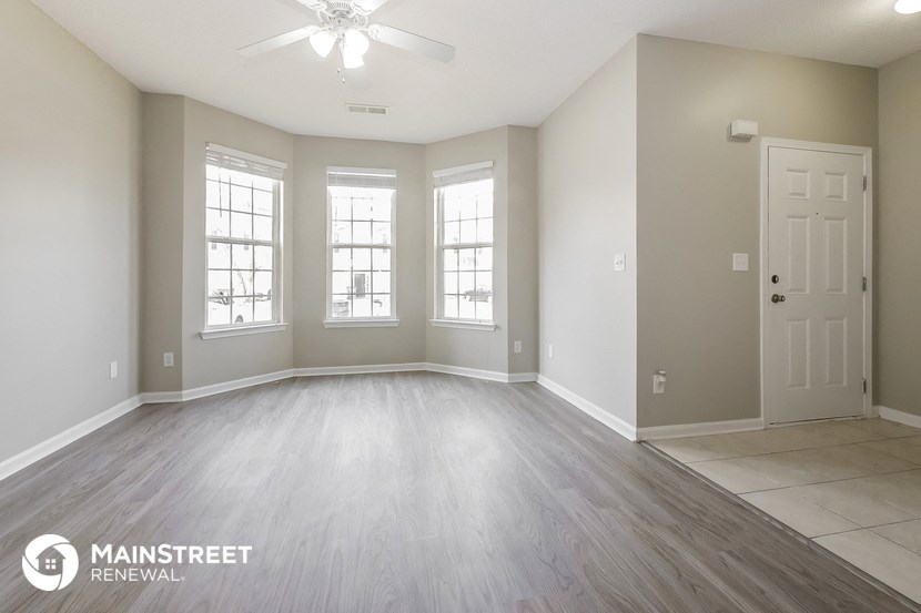 the living room of a new home with white and gray walls and wood flooring