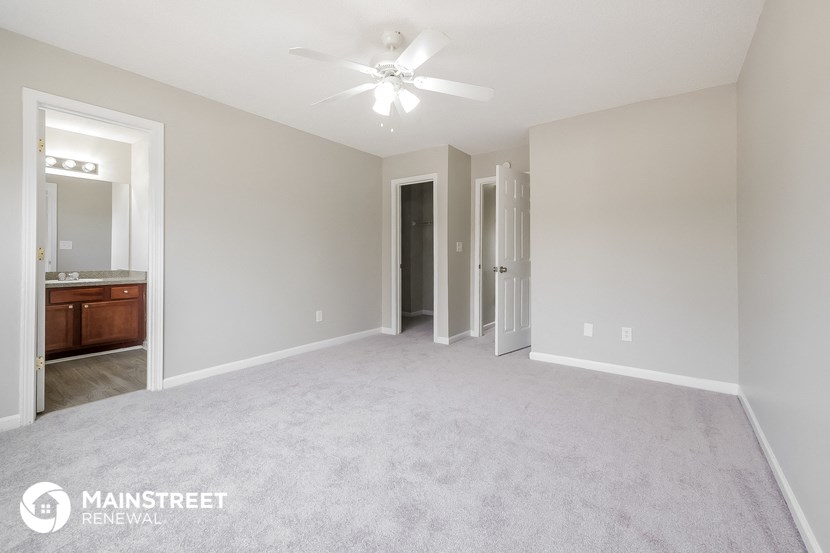 an empty living room with a ceiling fan and a bathroom