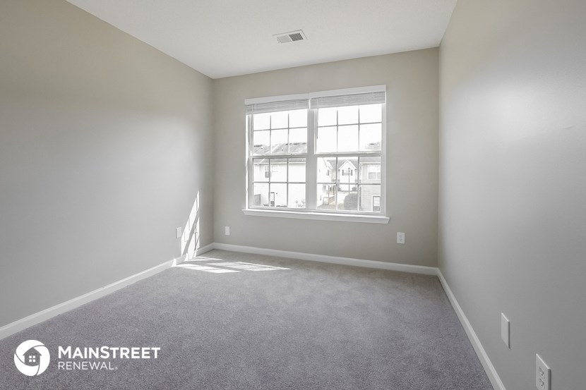 a bedroom with a window and carpeted floor